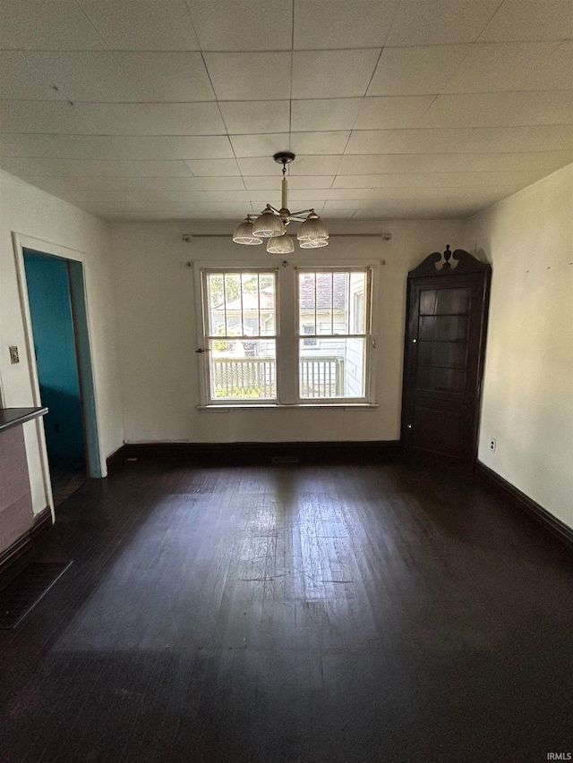 empty room featuring a chandelier and dark hardwood / wood-style flooring