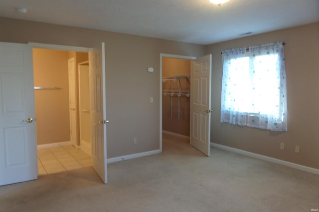 unfurnished bedroom featuring light colored carpet, a closet, and a walk in closet