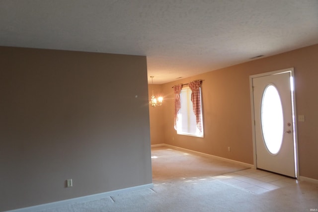 carpeted foyer with a textured ceiling and a chandelier