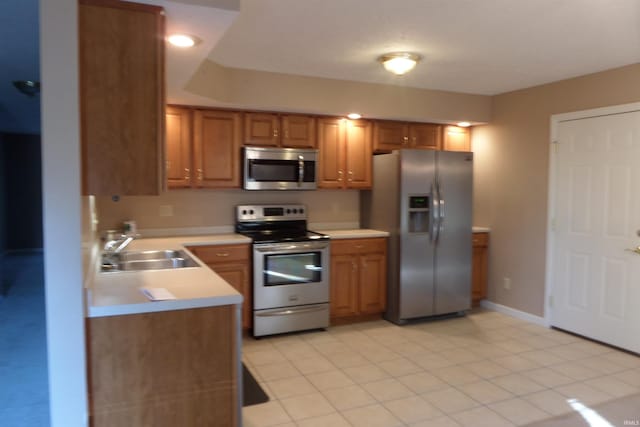 kitchen with appliances with stainless steel finishes, light tile patterned flooring, and sink