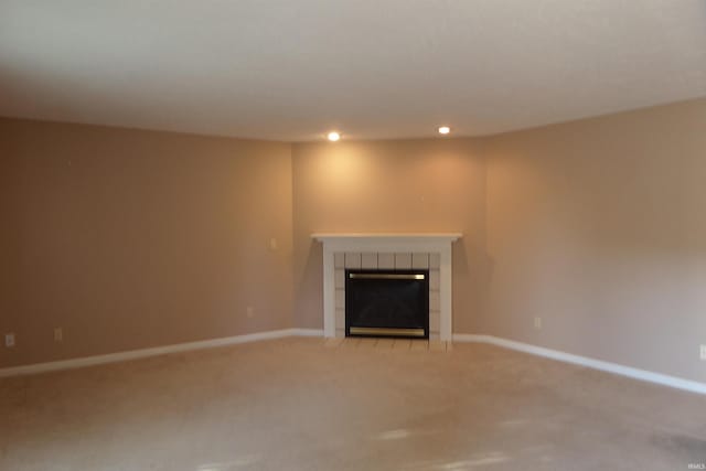 unfurnished living room with a tiled fireplace and light colored carpet