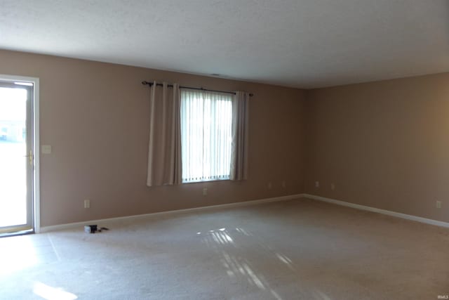 carpeted empty room featuring a textured ceiling and a healthy amount of sunlight