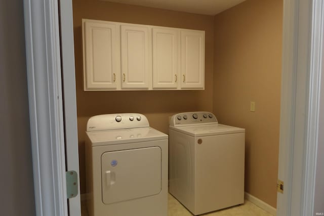 laundry room featuring washing machine and clothes dryer and cabinets