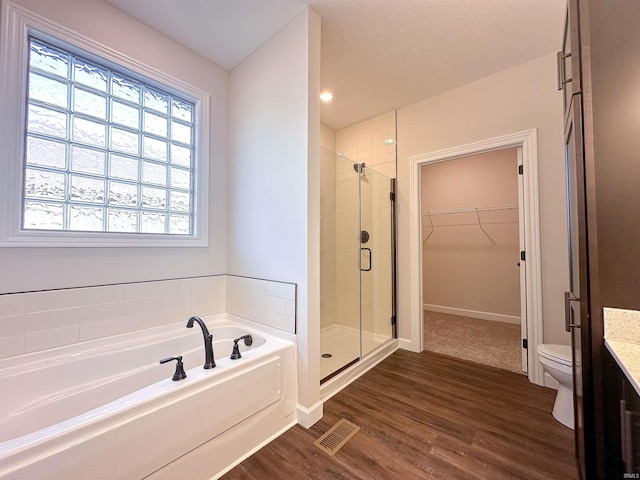 full bathroom with a textured ceiling, hardwood / wood-style flooring, independent shower and bath, vanity, and toilet