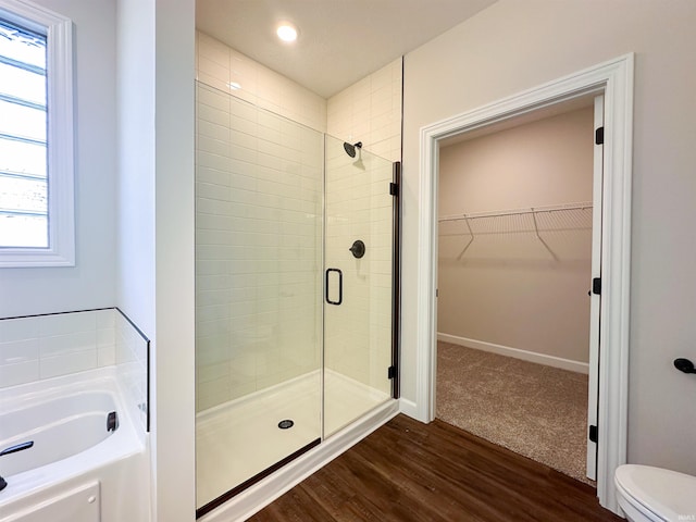 bathroom featuring wood-type flooring, shower with separate bathtub, plenty of natural light, and toilet