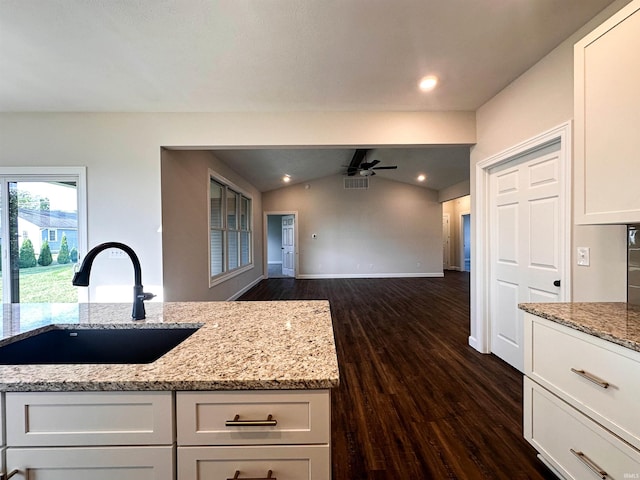 kitchen featuring lofted ceiling with beams, white cabinets, light stone countertops, dark hardwood / wood-style flooring, and ceiling fan