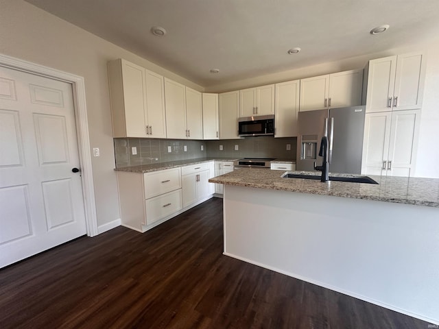 kitchen featuring light stone counters, appliances with stainless steel finishes, dark wood-type flooring, and white cabinetry