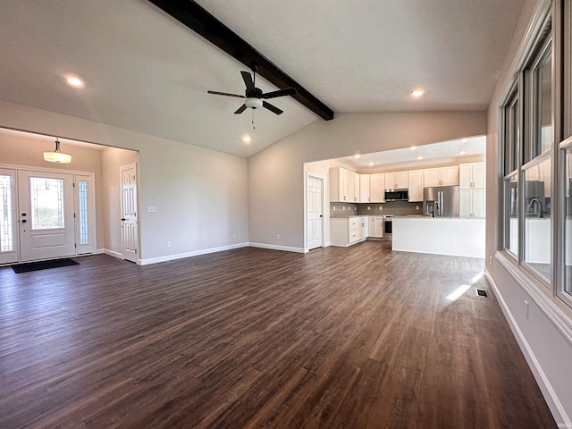 unfurnished living room with ceiling fan, lofted ceiling with beams, and dark wood-type flooring