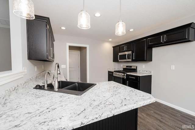 kitchen with stainless steel appliances, hanging light fixtures, sink, and dark hardwood / wood-style flooring