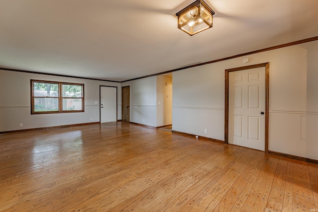 spare room with light wood-type flooring and crown molding