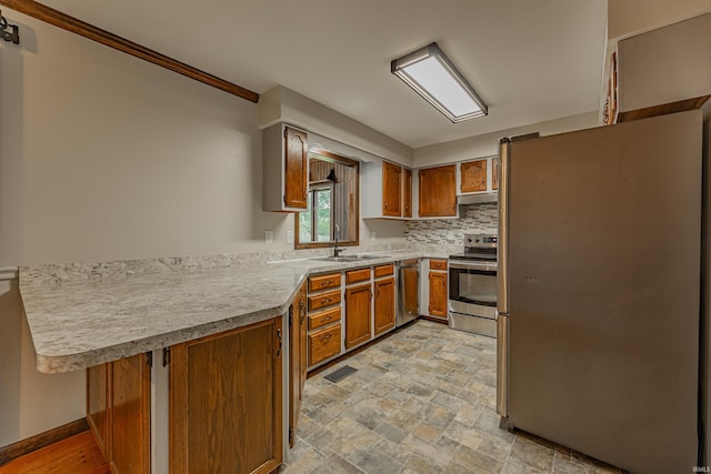 kitchen featuring sink, kitchen peninsula, decorative backsplash, stainless steel appliances, and ornamental molding