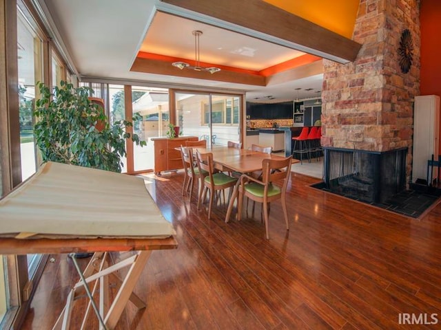 dining space with a raised ceiling, a fireplace, and hardwood / wood-style flooring