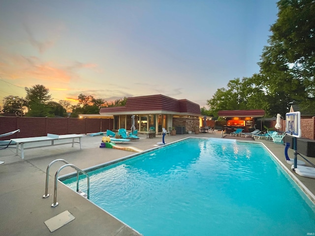 pool at dusk featuring a patio