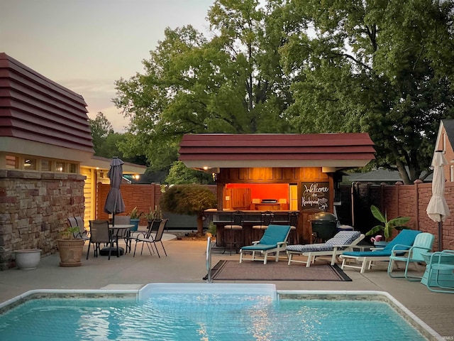 pool at dusk featuring a patio area