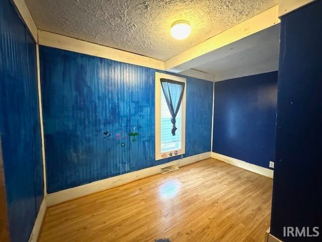 spare room with wood-type flooring and a textured ceiling