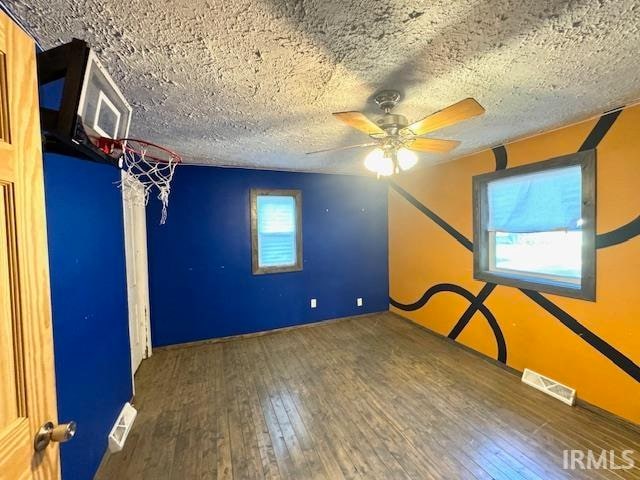 unfurnished room with a textured ceiling, wood-type flooring, and ceiling fan