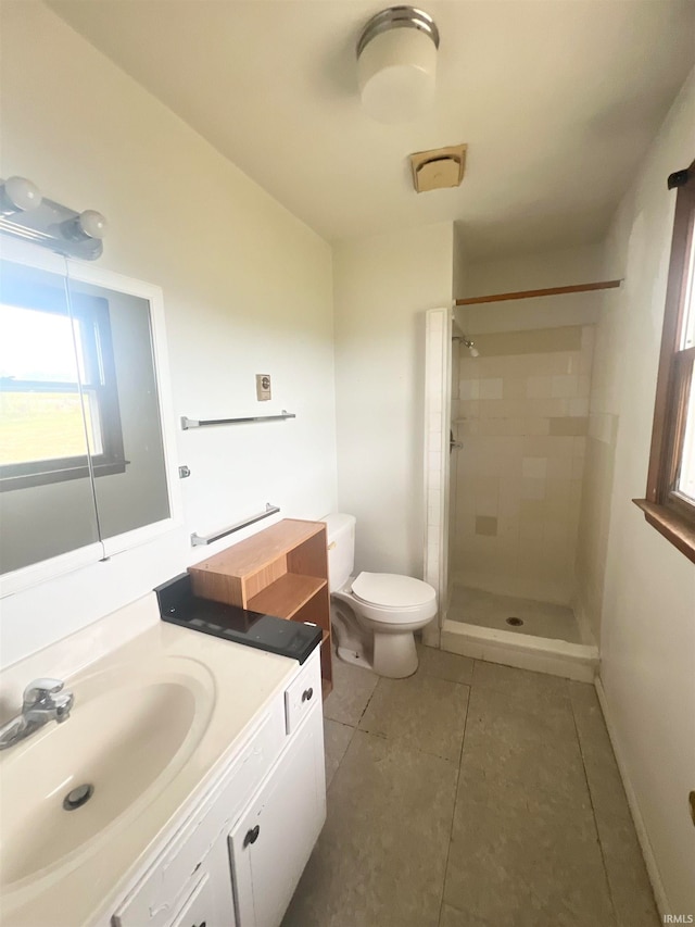 bathroom with a tile shower, tile patterned flooring, vanity, and toilet