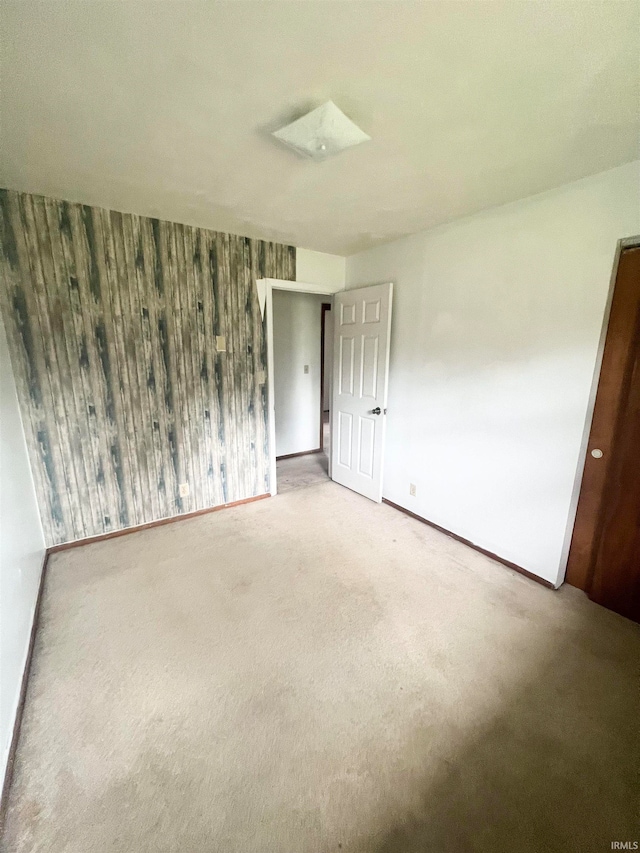 carpeted empty room featuring wood walls