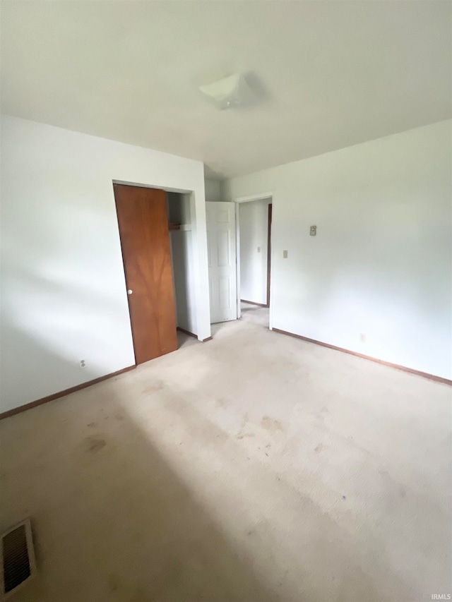 unfurnished bedroom featuring light colored carpet and a closet