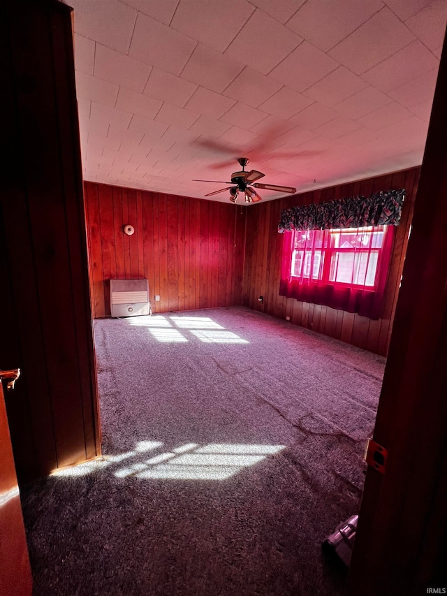 carpeted spare room with wood walls and ceiling fan