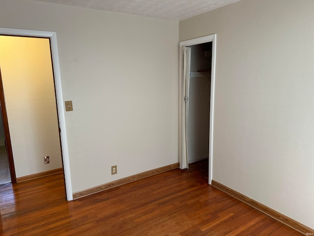 unfurnished bedroom featuring a textured ceiling, a closet, and dark hardwood / wood-style floors