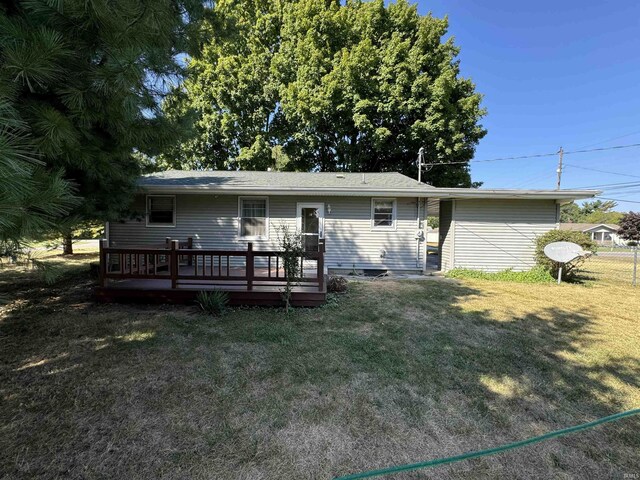 rear view of property featuring a wooden deck and a lawn