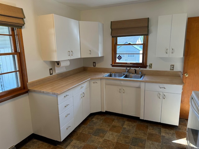 kitchen featuring white electric stove, sink, and white cabinetry