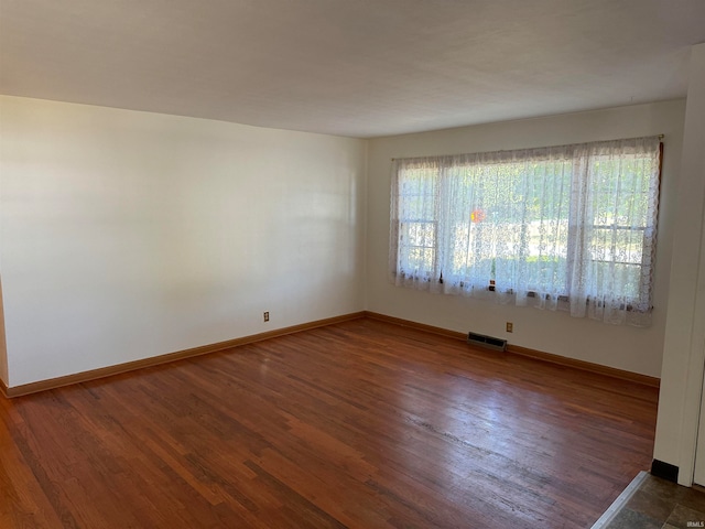 empty room with a wealth of natural light and dark wood-type flooring