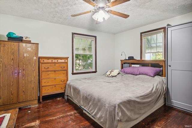 bedroom with multiple windows, dark hardwood / wood-style floors, ceiling fan, and a textured ceiling