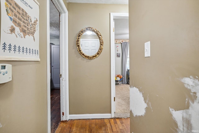 corridor featuring wood-type flooring and a textured ceiling