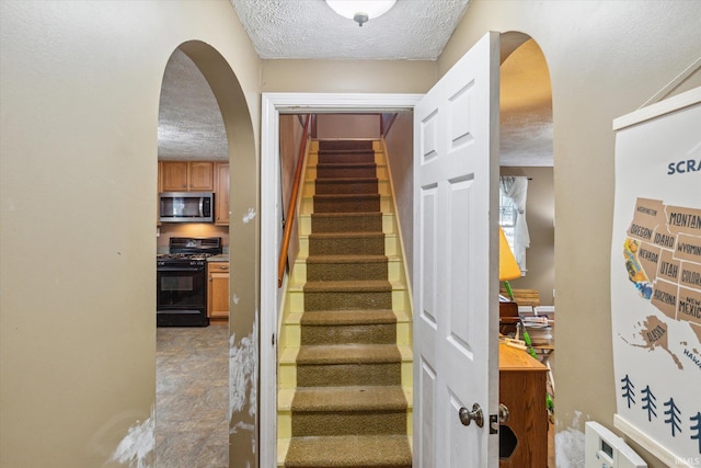 staircase featuring a textured ceiling