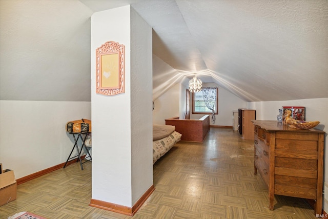 bedroom with a textured ceiling, vaulted ceiling, and parquet flooring