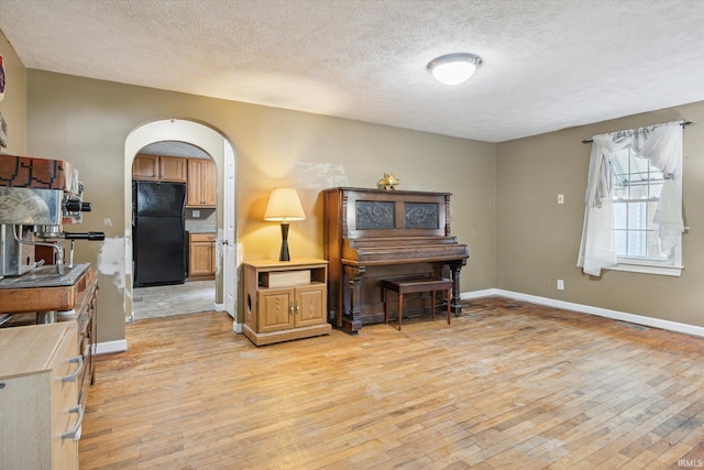 interior space with light hardwood / wood-style flooring, a textured ceiling, and black fridge