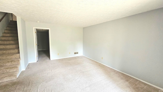 spare room featuring a textured ceiling and light colored carpet