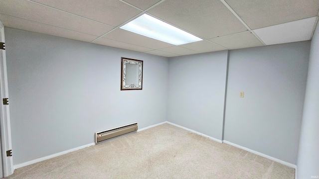 empty room with carpet, a drop ceiling, and baseboard heating