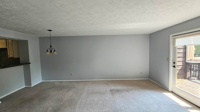 unfurnished living room with an inviting chandelier, a textured ceiling, and carpet