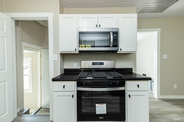 kitchen featuring appliances with stainless steel finishes, a textured ceiling, light hardwood / wood-style flooring, and white cabinetry