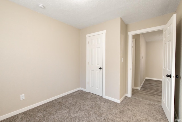 unfurnished bedroom featuring light carpet, a textured ceiling, and a closet