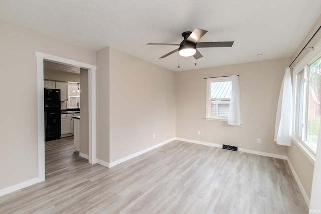 unfurnished room with plenty of natural light, ceiling fan, light wood-type flooring, and a textured ceiling