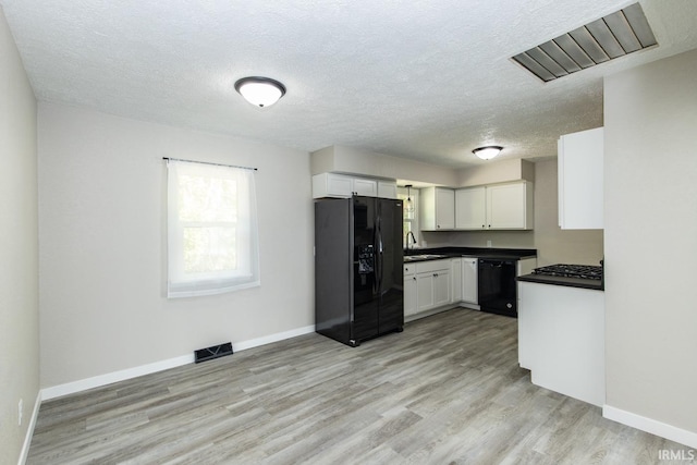 kitchen with black appliances, light hardwood / wood-style floors, white cabinetry, and a textured ceiling