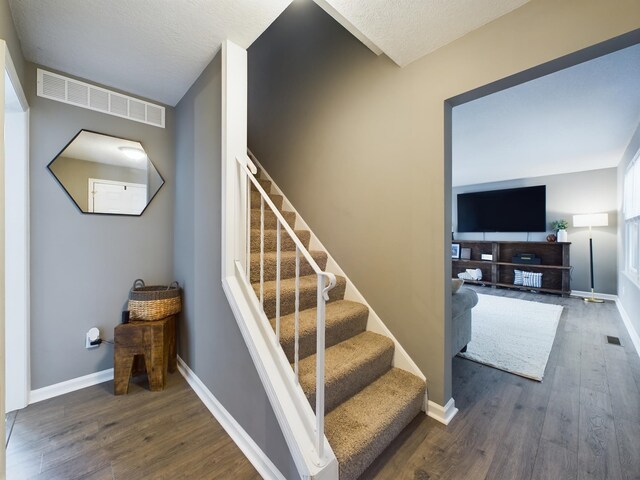 stairs with wood-type flooring and a textured ceiling