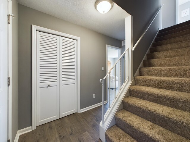 stairway with a textured ceiling and hardwood / wood-style floors