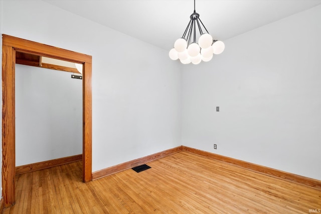 empty room with an inviting chandelier and hardwood / wood-style floors