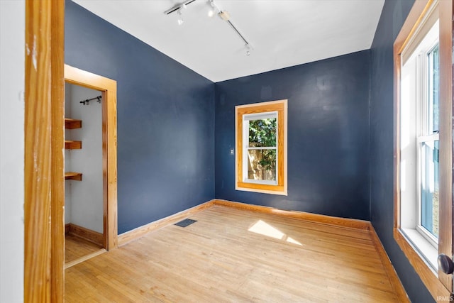 spare room featuring hardwood / wood-style floors and rail lighting