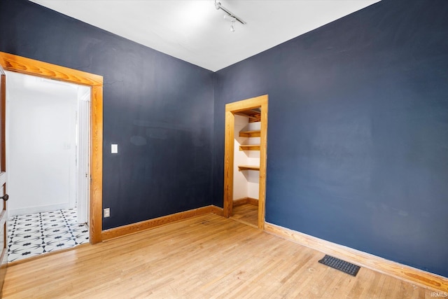 empty room featuring rail lighting and hardwood / wood-style floors