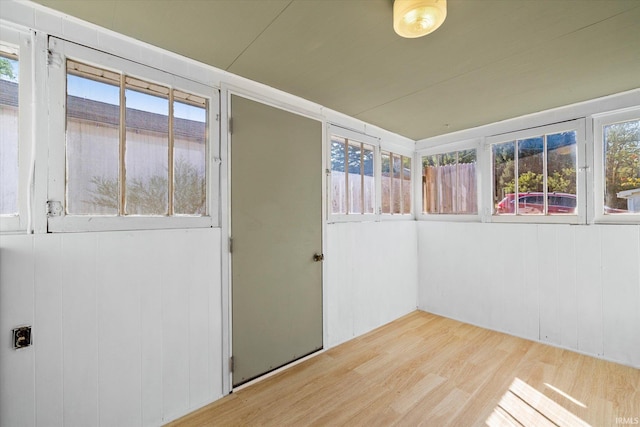 empty room with light hardwood / wood-style flooring and wood walls