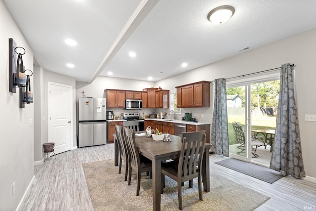 dining room featuring a textured ceiling, sink, and light hardwood / wood-style flooring