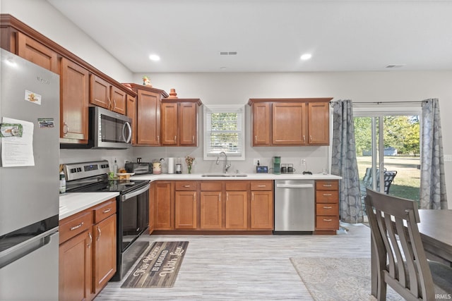 kitchen with light hardwood / wood-style floors, appliances with stainless steel finishes, plenty of natural light, and sink