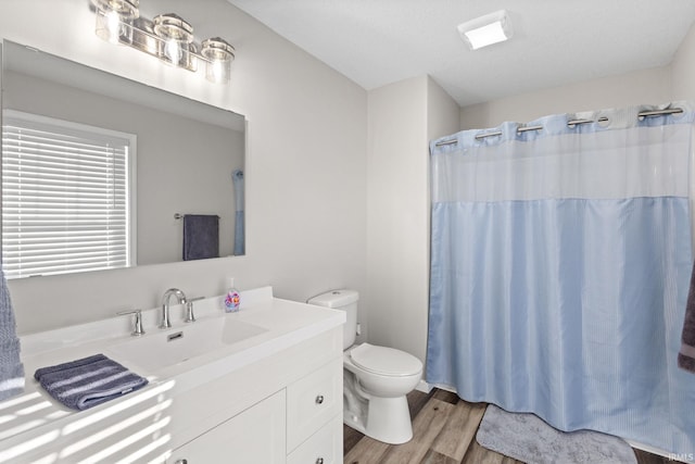 bathroom featuring wood-type flooring, a textured ceiling, a shower with shower curtain, vanity, and toilet