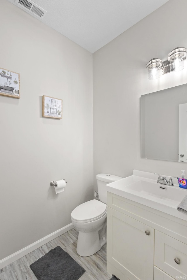 bathroom with hardwood / wood-style flooring, vanity, and toilet